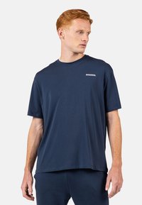 Námořnická modrá tričko s krátkým rukávem vyrobené z měkké látky. Má kulatý výstřih a na přední straně bílé logo "ROSSIGNOL". Jednoduchý design.