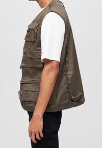 Fischereiweste in Olivgrün aus strapazierfähigem Stoff, mit mehreren vorderen Taschen, einer Reißverschlusstasche und lockerem Schnitt.