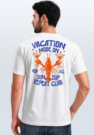 Mann mit dunklen Haaren und Bart trägt ein weißes T-Shirt mit einem orangefarbenen Hummer, der zwei Cocktailgläser hält, und blauem Text mit der Aufschrift "Vacation mode on Sun Sip Repeat Club."
