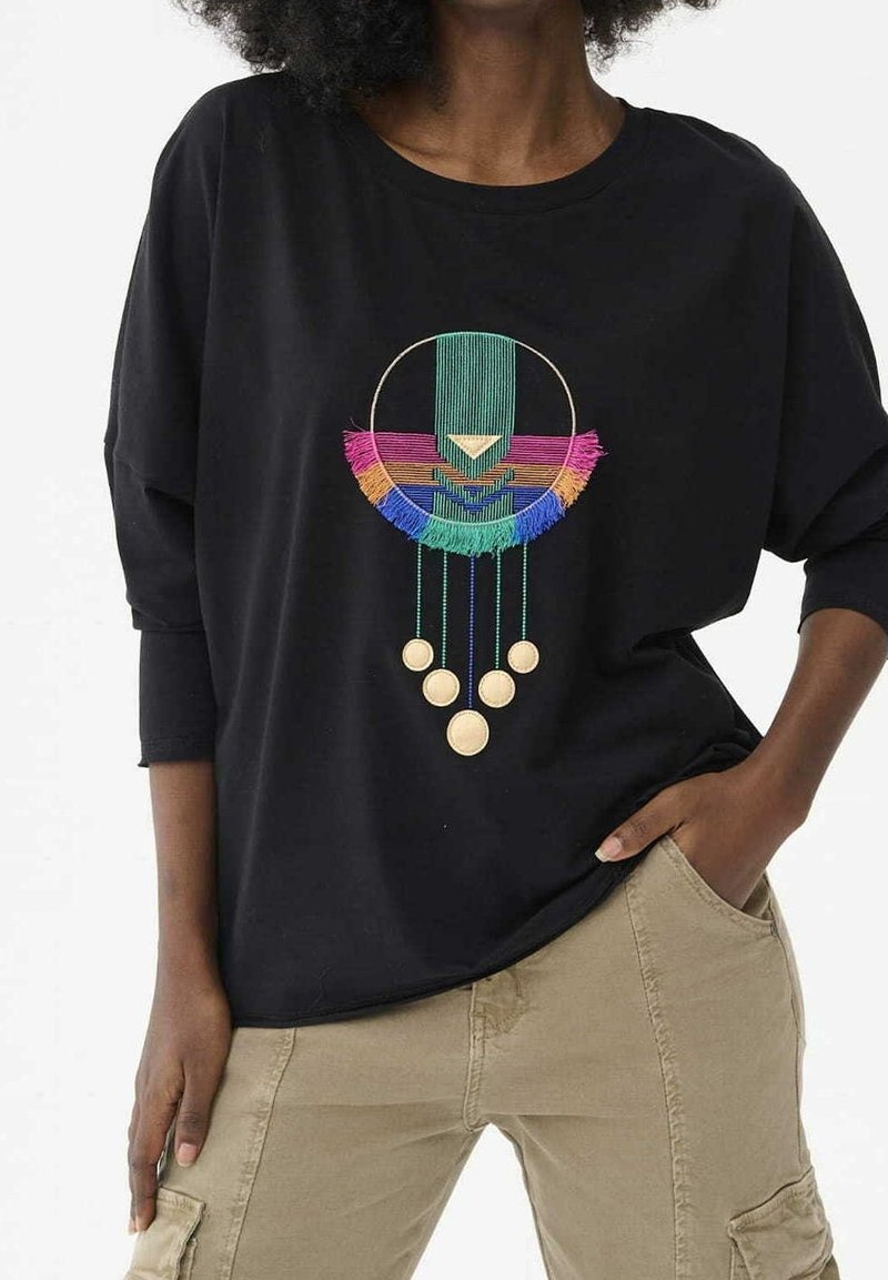 T-shirt noir oversize avec motif brodé multicolore de formes géométriques et pompons, col rond et manches longues.