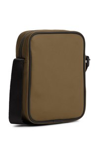 Μικρή ορθογώνια τσάντα ώμου σε ελιά πράσινο με μαύρο ρυθμιζόμενο λουράκι και φερμουάρ, παρουσιάζεται στραμμένη σε λευκό φόντο.