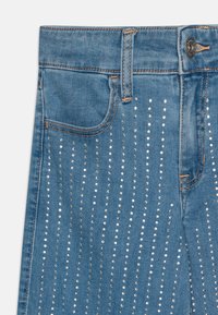 Lyseblå jeans laget av denim med vertikale rader av sølvnagler, en enkelt baklomme og et klassisk fem-lommers design.