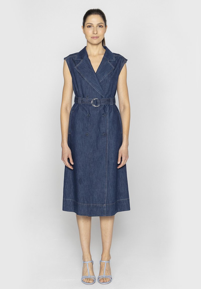 Sukienka midi z denimu o podwójnym zapięciu, pasek w talii, rękawy typu cap oraz jasnobrązowe przeszycia. W zestawie z jasnoniebieskimi sandałami na obcasie.