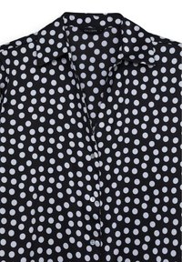 Schwarzes Shirt mit großen weißen Polka-Dots, Kragen und Knopfverschluss vorne. Glattes Material mit lockerer Passform und kurzen Ärmeln.