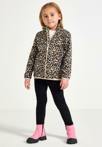 Leopardprint fleecejakke med høj krave og gylden lynlås, parret med sorte leggings og rosa lynlås støvler. Glat tekstur, afslappet design.