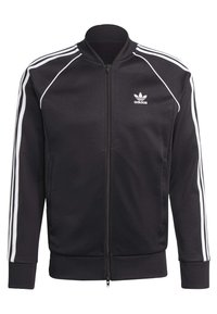 Melna zip-up jaka, izgatavota no gluda poliestera, ar baltām svītrām uz piedurknēm, ribotām aprocēm un mazu baltu logo uz krūšu daļas.