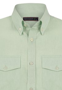Camisa de botones de color verde claro con cuello, dos bolsillos en el pecho y botones blancos. La tela tiene un aspecto texturizado y ligeramente arrugado.