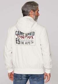 White hooded jacket with elastic cuffs and hem, featuring a large back graphic in gray and red text that reads "CAMP DAVID TrailMark E5 THE ALPS."