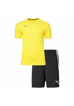 Gelbes Kurzarmhemd und schwarze Shorts im Set, ausgestattet mit einem strukturierten Stoff und weißen Akzenten an den Shorts und dem Logo.