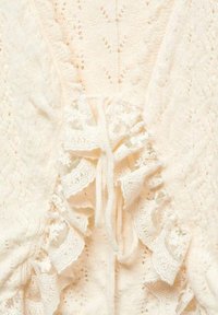 Kremowy kardigan z dzianiny z koronkowym wykończeniem, z falbankami i zapięciem na sznurek, prezentujący delikatny, misterny wzór.