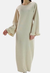 Vestido largo color beige claro hecho de tela texturizada, con cuello redondo, mangas sueltas y puños fruncidos. Diseño hasta el suelo con un ajuste relajado.
