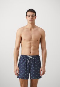 Badeshorts i marineblå med et gentagende grønt logomønster, elastisk talje med hvid snor, kort længde, letvægtsmateriale.
