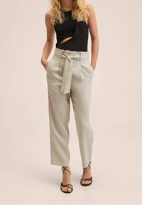 Jasnoszare, wysokie spodnie z troczkiem, plisami z przodu i kieszeniami. Połączone z czarnym bezrękawnikem i czarnymi sandałami.