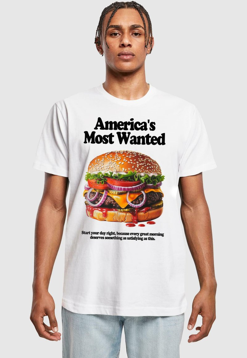 Hvid T-shirt med et farverigt grafisk design af en burger med sesamfrøbolle, salat, tomat, løg og dryppende sauce, plus tekst ovenfor og nedenfor.