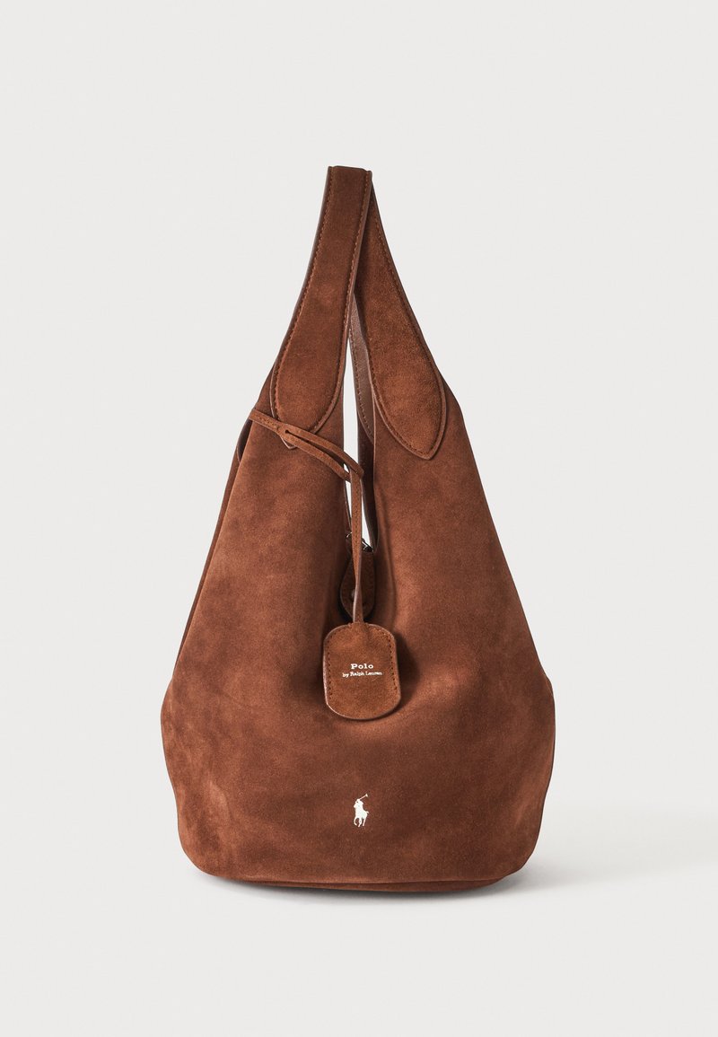 Sac d'épaule en daim marron avec une sangle unique, fermeture à cordon, logo Polo Ralph Lauren et étiquette en cuir marquée sur fond neutre.