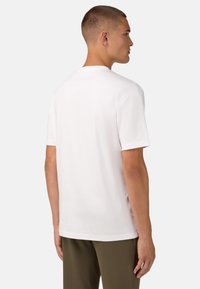 Balta kokvilnas T-krekls ar īsajām piedurknēm, apaļu kaklu un vienkāršu aizmugures dizainu. Audums izskatās gluds un viegls.