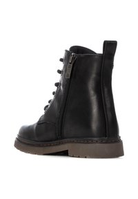 Botín negro de cuero hasta el tobillo con cremallera lateral, puntera redonda, parte delantera con cordones y suela de goma texturizada con un borde marrón en contraste.