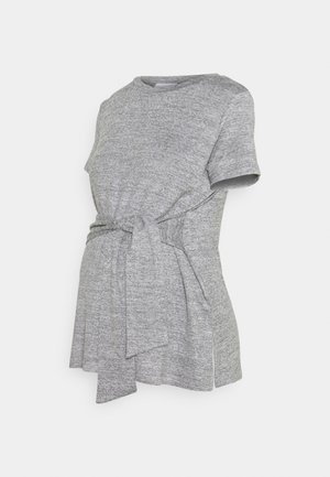 Szara koszulka ciążowa z krótkim rękawem, okrągłym dekoltem i wiązanym z przodu detalem dla regulowanego dopasowania wokół brzucha.