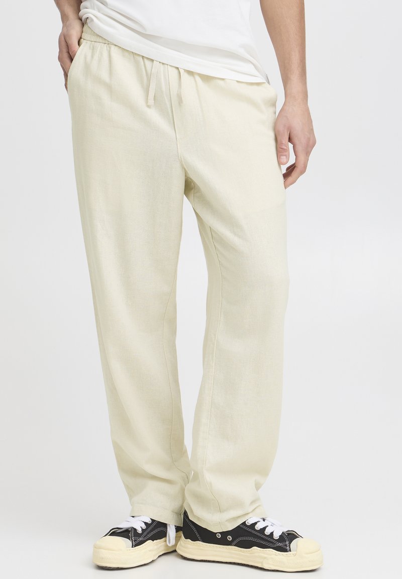 Lyse beige loungebukser lavet af et blødt, tekstureret stof. Har elastisk talje med snøre, sidelommer og en afslappet pasform.
