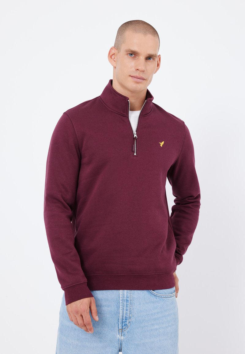 Burgundská mikina s čtvrtovým zipem a žebrovaným límcem, přední zip a malé žluté logo na hrudi. Měkká, texturovaná látka.