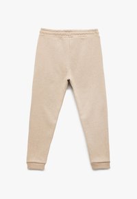 Beige joggere med en blød tekstur, elastisk talje og tætsiddende manchetter ved anklerne. Simpel design uden mønstre eller udsmykninger.