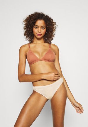 Bralette- en bikinitop in terracotta- en nude-kleuren. De bh heeft een driehoekontwerp met dunne bandjes, en de bikini heeft een hoge uitsnede.