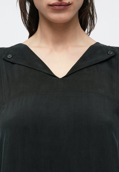 Μαύρο πουκάμισο με V-λαιμόκοψη και γιακά που διπλώνει, διακριτική γυαλάδα και δύο κουμπιά στον ώμο. Λεπτή υφή και εφαρμοστή γραμμή.
