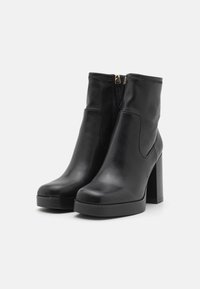 Botas de cuero negro hasta el tobillo con un tacón grueso, textura suave, puntera redondeada, cierre de cremallera lateral y diseño minimalista.