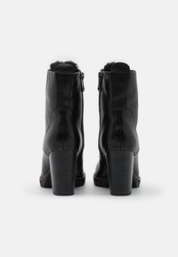 Sorte ankelstøvler i læder med en glat overflade, to sidelommer med lynlås og blokhæl. Toppen har en blød foring.