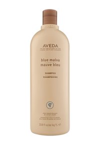 Shampoo Aveda Blue Malva dans une bouteille en plastique beige, de forme arrondie, avec un capuchon à rabat marron et un étiquetage minimaliste à l'avant.
