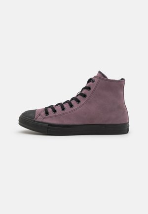 Hochschuh-Sneaker aus lila Wildleder mit schwarzer Gummikappe und -sohle. Mit schwarzen Schnürsenkeln und einem kleinen Markenlogo auf der Ferse.