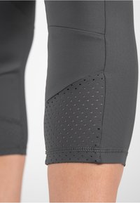 Grijze sportleggings van een textuurstof met meshpanelen en kleine perforaties nabij de zoom, waardoor de ademendheid en pasvorm worden verbeterd.