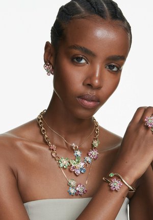 Conjunto de joyería con temática floral que presenta cadenas en tono dorado, piedras preciosas de colores en rosa, verde y azul, con pendientes, collar y pulsera a juego.