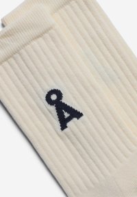 Cremfarbene, gerippte Socken mit einem dunkelblauen Logo. Hergestellt aus weichem Material mit einer gestrickten Textur, die Komfort und Passform bietet.