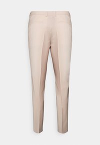 Pantalons beiges sur mesure avec une coupe slim, présentant une taille plate, des passants de ceinture et deux poches avant. Tissu lisse avec un léger éclat.