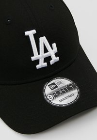 Czarna czapka baseballowa wykonana z bawełny z zakrzywionym daszkiem. Ma białe haftowane logo "LA" oraz okrągłą metkę New Era z napisem "9FORTY ADJUSTABLE."