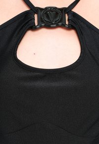 Top halter preto com decote redondo e um detalhe decorativo em metal preto ao centro. Tecido suave com ligeiro brilho.