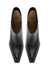 Botas de cuero negro hasta el tobillo con un diseño de punta afilada, textura suave y estilo minimalista. El interior presenta un forro marrón claro y sin herrajes visibles.