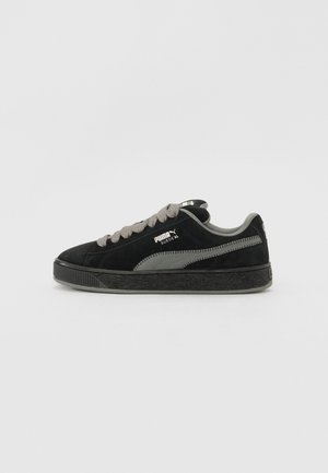 Zwarte Puma Suede XL sneaker met grijze veters, grijze logostreep en zwarte gestructureerde zool, zijaanzicht op een effen witte achtergrond.
