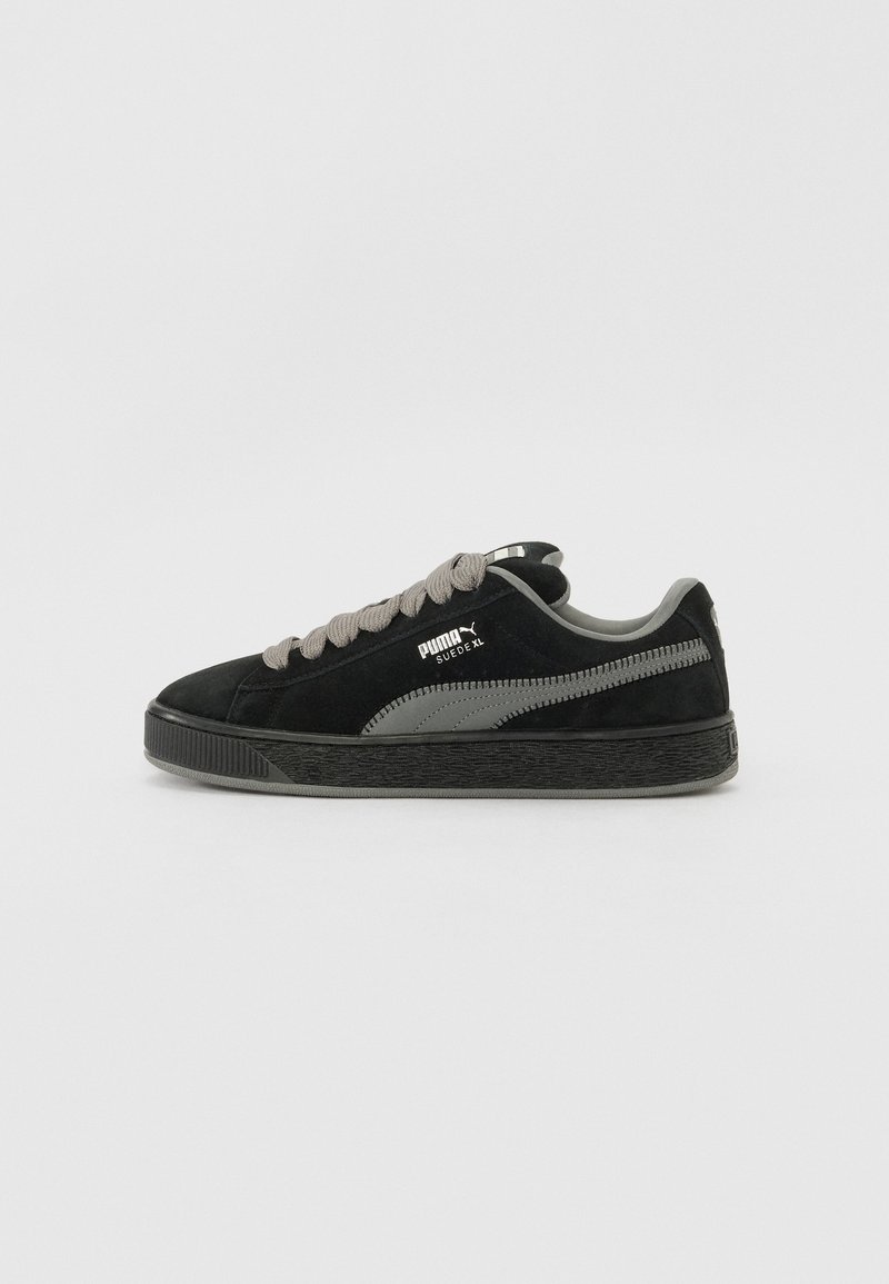 Baskets Puma Suede XL noires avec lacets gris, bande logo grise et semelle noire texturée, vue de côté sur fond blanc uni.