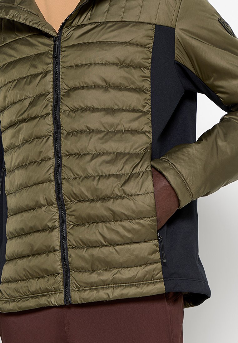 Gewatteerde jas met een olijfgroene en zwarte kleurstelling, ritssluiting, ribbelstructuur en zijzakken voor functionaliteit.