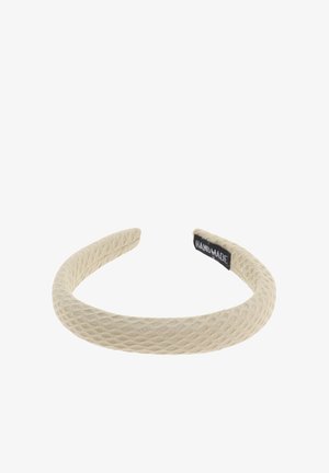 Beige stoffen hoofdband met een gestructureerd, geweven patroon. Ronde vorm met een zwart label aan de binnenkant met de tekst "HAND MADE".