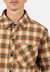Orange-weiße karierte Flanellhemd mit Knopfleiste, spitzem Kragen und einer Brusttasche mit Logo. Weiches Material.