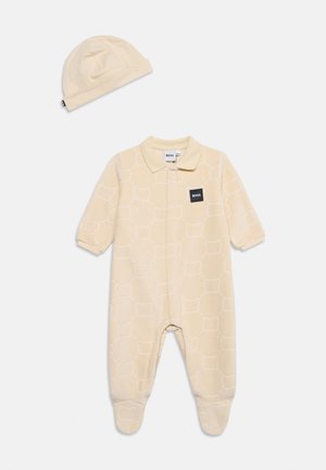 Beige baby heldragt med fødder, subtilt mønster og krave, kombineret med matchende blød hue, begge med BOSS-logo patches.