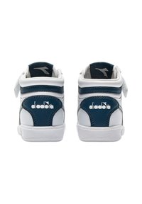 Sneaker alte bianche e navy con fascia in velcro, caratteristiche di tessuto testurizzato, accenti lisci e un logo sul tallone.