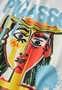 Vitt tyg med en djärv grafisk design i Picasso-stil, som visar livliga färger: röd, gul, grön och blå. Texten "PICASSO" är i ljusblått.