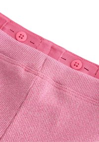 Rosa ribstrikket stof med metalliske tråde, med en taljebånd med to knaplukninger og en enkelt rosa knapdetalje.