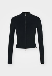 Svart ribbad stickad långärmad kort jacka med hög hals och silverfärgad dragkedja framtill på enfärgad vit bakgrund.