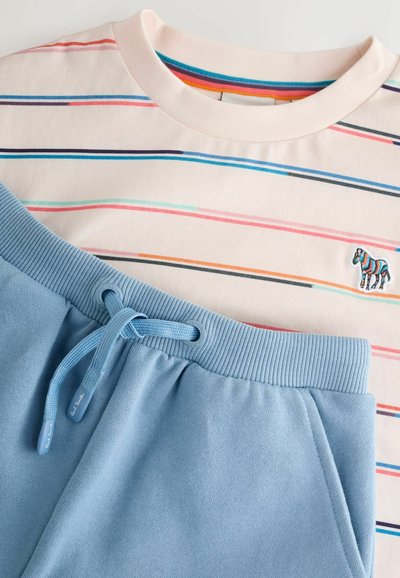 Camiseta de cuello redondo con rayas horizontales multicolores y una pequeña cebra multicolor bordada, combinada con pantalones deportivos de cuerda en azul claro.