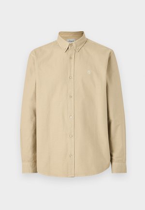 Béžová košeľa s dlhým rukávom na gombíky, s golierom na gombíky a malým logom na ľavej strane hrudníka, zobrazená na jednoduchom pozadí.